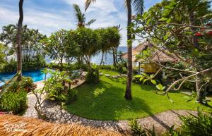 a resort yard with a swimming pool and palm trees at Santai Hotel in Amed