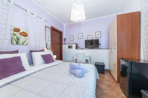 a bedroom with a large white bed with purple pillows at B&B Rita E Renzo in Riola Sardo