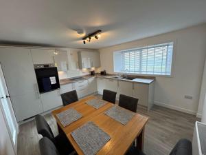 a kitchen with a wooden table and a table and chairs at Modern 3 bedroom house, Mossbank in Mossbank