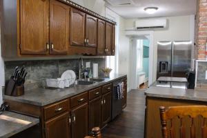 a kitchen with wooden cabinets and a stainless steel refrigerator at Newly Renovated Historic 6-Bedroom Manor, Where Timeless Elegance Meets Modern Luxury in Onancock