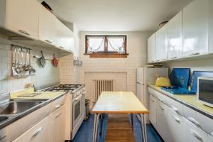 a kitchen with white cabinets and a table in it at Charming penthouse with breathtaking views in Cortina dʼAmpezzo