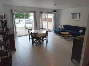 a living room with a blue couch and a table and chairs at Angenehmes Haus in Perros-Guirec