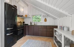 a kitchen with wooden cabinets and a black refrigerator at 4 Bedroom Stunning Home In Tisvildeleje in Tisvildeleje