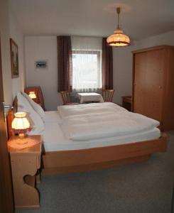 a bedroom with a large white bed and a table at Haus Auzinger in Schönau am Königssee