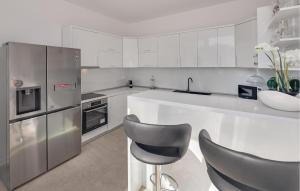a kitchen with stainless steel appliances and gray chairs at Nice Home In Vrvari With Wifi in Poreč