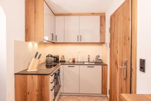 una piccola cucina con armadi bianchi e lavandino di Mocking Ferienappartements a Kitzbühel