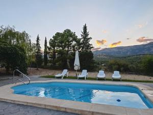 a swimming pool with two chairs and a umbrella at Casa El Rincón del Guardal in Huéscar