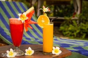two cocktails on a wooden table with fruit and flowers at Santai Hotel in Amed
