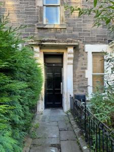 a black door to a brick building at Central Room In Historic Tenement Shared Apartment Near Old Town in Edinburgh