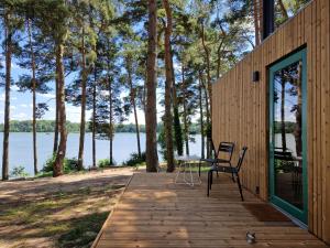 a wooden deck with a table and chairs on it at Tiny Houses & Schwedenhäuser Ahoi Camp Canow in Wustrow