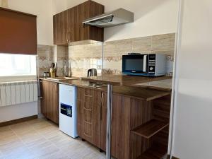 a kitchen with wooden cabinets and a microwave at Tolqyn apart hotel in Aktau