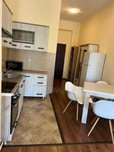 a kitchen with white cabinets and a table and chairs at Olympia Residence in Chişineu Criş +8 photos