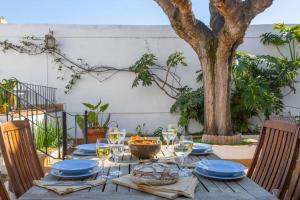 een houten tafel met wijnglazen en een boom bij Casa Colomer in Canet de Mar