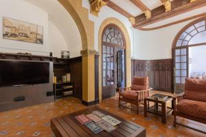 een woonkamer met een televisie en een bank en stoelen bij Casa Colomer in Canet de Mar