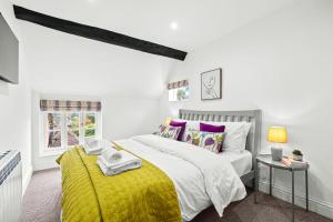 a bedroom with a large bed with a yellow blanket at Bell Cottage by Ludlow Castle with onsite parking in Ludlow