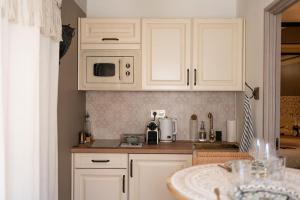 a kitchen with white cabinets and a counter top at Love Room 1001 nuits & Balnéo in Saint-Rambert-dʼAlbon