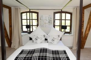a bedroom with a white bed with pillows and windows at Herberge der Alten Schule in Raddestorf