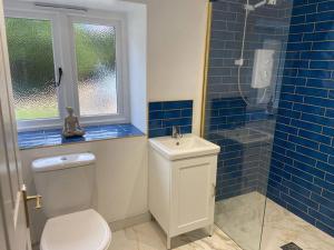 a blue tiled bathroom with a toilet and a shower at 2 bed cozy cottage in Wansford