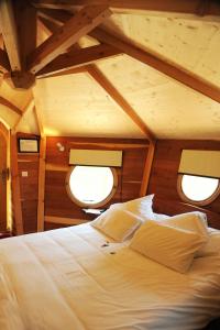 a bed in the middle of a room with two windows at Hôtel Restaurant Le Relais de l'Estuaire in Étauliers