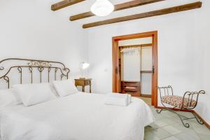 een witte slaapkamer met een bed en een stoel bij Villa el Pescador in Yaiza +17 foto's