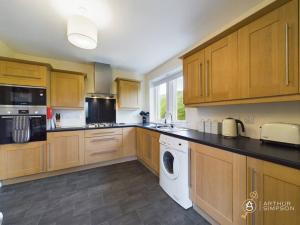 a kitchen with wooden cabinets and a washer and dryer at Dunard - Charming three bedroom cottage in Bigton in Sandwick +14 photos