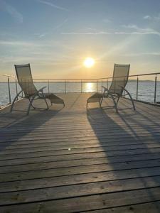 two chairs sitting on a pier with the sun setting at Hausboot Sophie in Stralsund in Stralsund