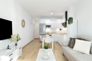 a white living room with a couch and a kitchen at Apartamento Calderon in Barbate