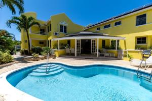a house with a swimming pool in front of a building at Vida Mejor - Poolside in Saint James