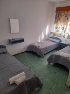 Tres camas en una habitación con suelo verde. en Hotel Pourally, en Villa Gesell