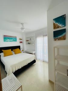 ein weißes Schlafzimmer mit einem Bett mit gelben Kissen in der Unterkunft Paraiso de costa in Playa de Gandia