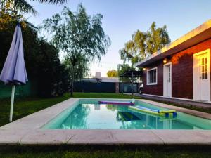 ein Swimmingpool mit Sonnenschirm neben einem Haus in der Unterkunft Casa Central in Roldán