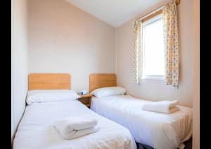 two twin beds in a room with a window at MP676 Parkdean Camber Sands in Camber +22 photos