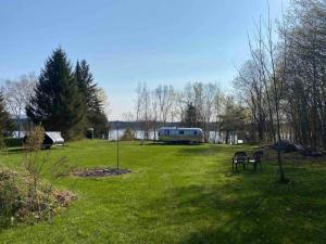 a park with a trailer and two chairs in the grass at Birches and Blueberries with Beach Access in East Charleston