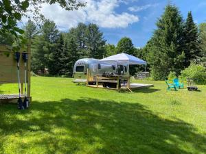 an rv parked in a field with a tent at Birches and Blueberries with Beach Access in East Charleston