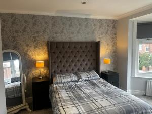 a bedroom with a bed and two lamps and a mirror at Two the Manor Born 3 bedroom house in Tynemouth