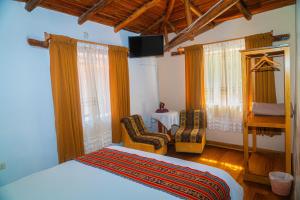 Un dormitorio con una cama y dos sillas y un televisor. en Casa de Ollanta ByB, en Ollantaytambo