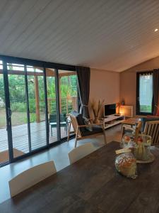 a living room with a table and chairs and sliding glass doors at Chalet la lande in Ondres