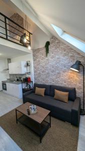 a living room with a couch and a brick wall at Le Loft proche aéroport CDG I Paris I Astérix in Dammartin-en-Goële
