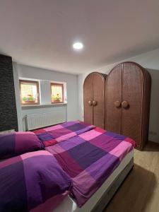 a bedroom with a bed with a purple and purple comforter at Apache Königswinter in Königswinter