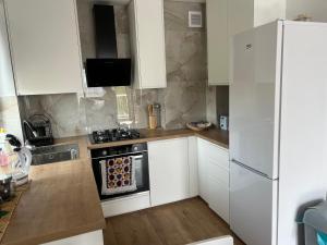 Eine Küche mit weißen Schränken, Herd und Kühlschrank in der Unterkunft U Ani in Lyck