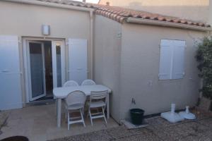a white table and chairs sitting outside of a house at à 900m de la plage sur Oléron in Dolus-d'Oléron