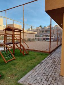 a wooden playground with a tennis court in the background at Flecheiras in Trairi