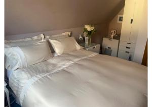 un letto bianco con cuscini bianchi e un vaso di fiori di Carmichael a Edimburgo
