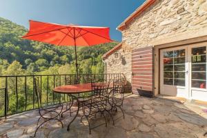 un tavolo e sedie con ombrellone su un balcone di Chapelle de Léca, Authentique Chapelle Rénovée - Vallespir - Vue Imprenable Montagne - Unique, Loft Moderne et Pittoresque - WIFI - Confort Premium - OFFRE SPECIALE - Majestic Key Konciergerie Collioure a Corsavy Altre 20 foto