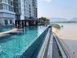 a swimming pool next to a building and a body of water at House Of 99 in Kuantan