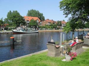 people sitting in chairs by a river with a boat at Ferienwohnung mitten in der City in Wilhelmshaven