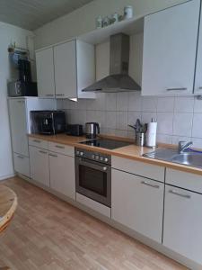 a kitchen with white cabinets and a stove top oven at Ferienwohnung mitten in der City in Wilhelmshaven +14 photos
