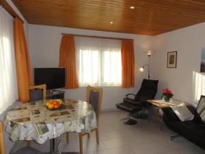 ein Wohnzimmer mit einem Tisch und einem TV in der Unterkunft Apartment Beck in Wilderswil