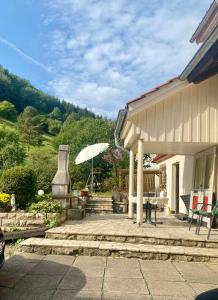 a patio with an umbrella next to a house at Ferienwohnung GARTENBLICK im HAUS GERLACH in Walkenried