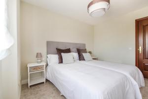 Un dormitorio blanco con una gran cama blanca y una mesa. en El Jardín de Estrella, en Navacerrada